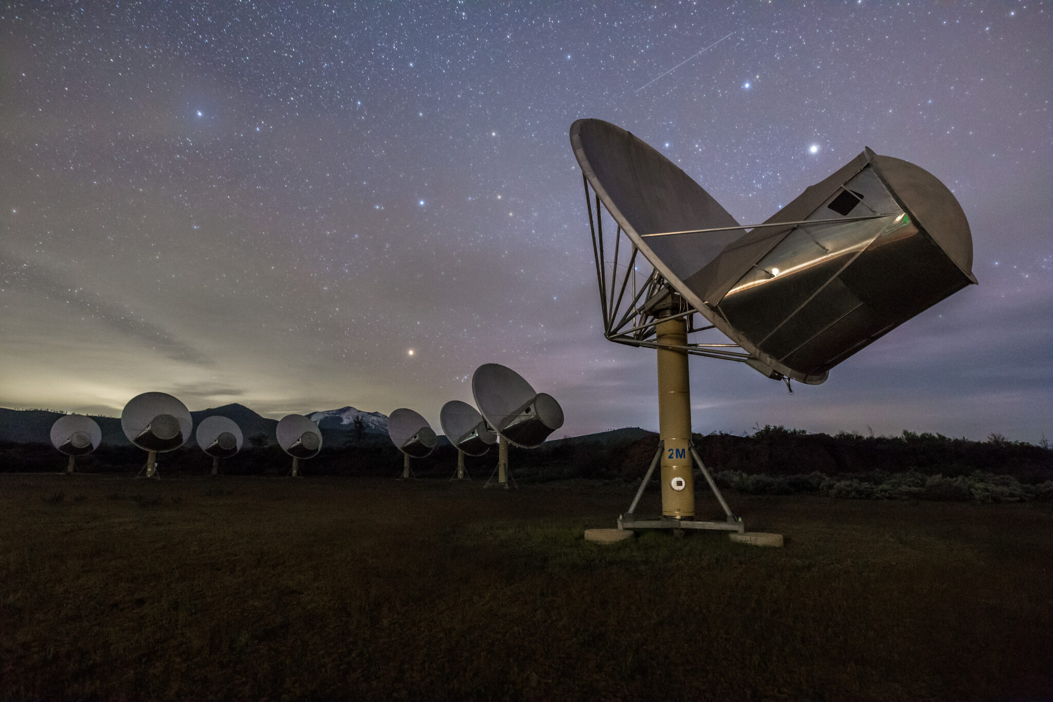 Radio dishes at the Allen Telescope Array beneath a star-filled night sky.